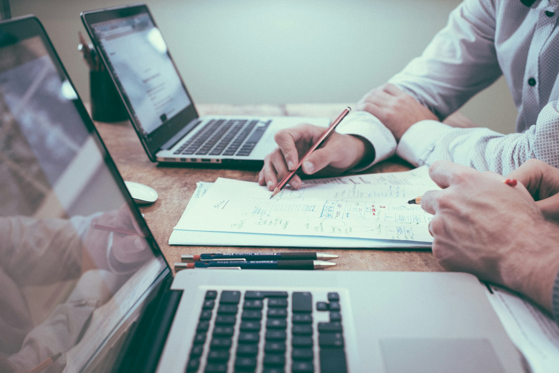 Two individuals writing notes and working on laptops, representing government investigations and regulatory enforcement actions in Ontario and Quebec. | Deux personnes prenant des notes et travaillant sur des ordinateurs portables, représentant les enquêtes gouvernementales et les mesures d’application réglementaire en Ontario et au Québec.