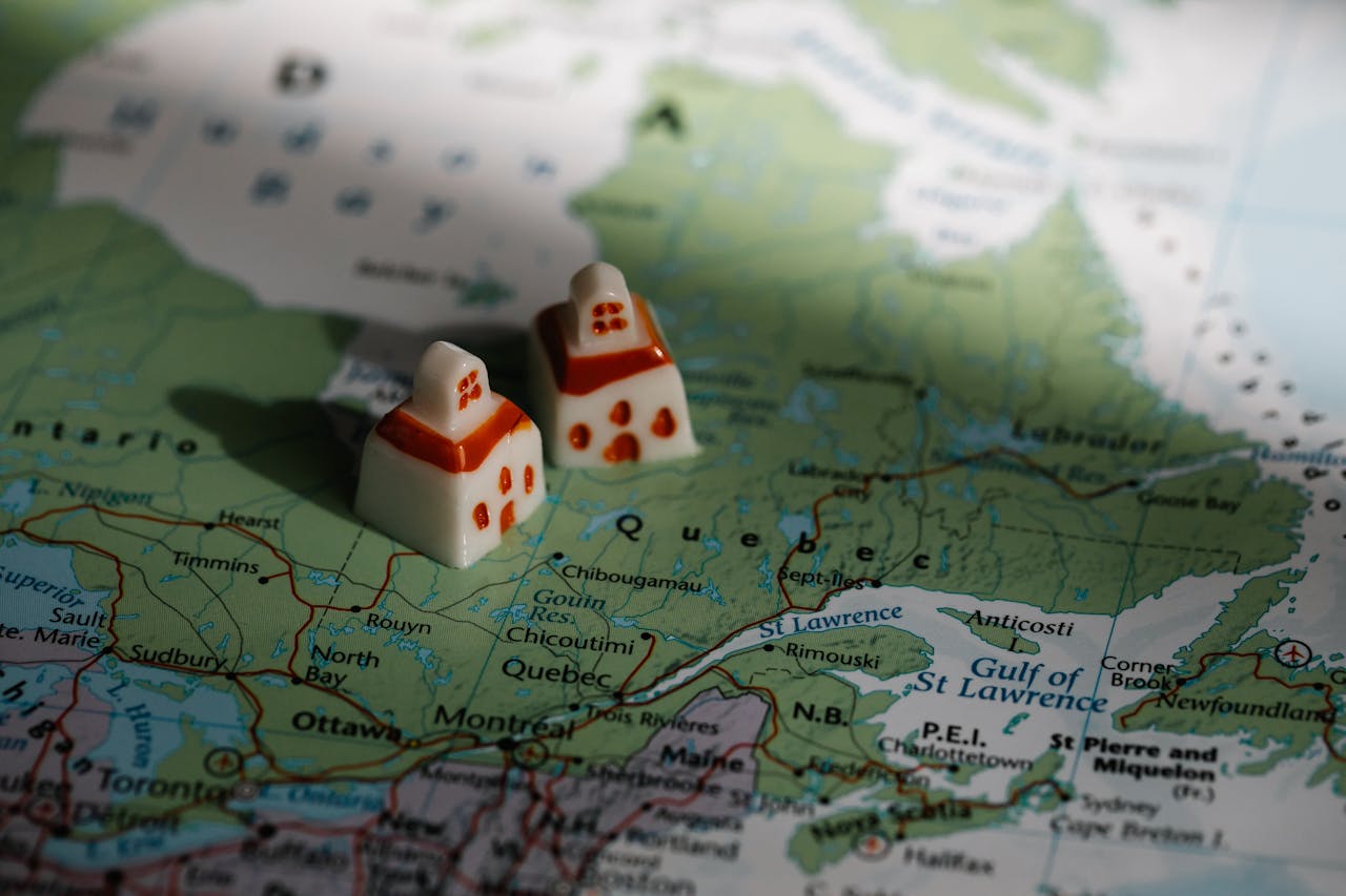 Close-up of a map of Québec, with two small house figurines sitting on it, representing the Supreme Court of Canada's recent decision on Québec's electoral boundaries legislation. | Gros plan d’une carte du Québec sur laquelle reposent deux petites figurines de maison, représentant la récente décision de la Cour suprême du Canada concernant la législation québécoise sur les limites des circonscriptions électorales.