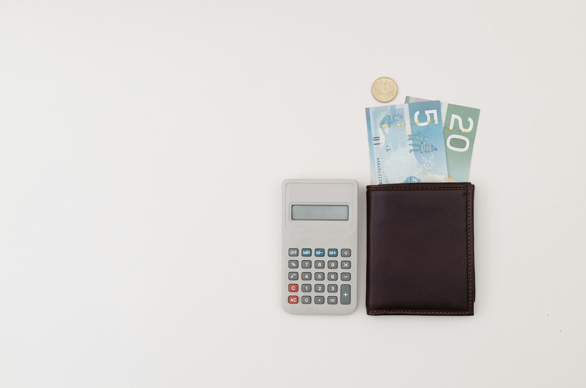 A calculator and a wallet sitting on a table representing CRA or Revenu Québec tax collection.